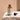 An amber glass dropper bottle labeled 'Medité Invictus Essential Hair Revival Oil' sits on a textured stone surface with its black dropper cap placed beside it against a warm beige background.