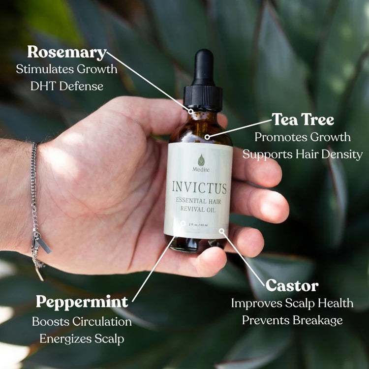 Hand holding Invictus hair growth oil with its four ingredients labeled: rosemary, tea tree, peppermint and castor