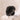 Black silicone grooming brush with multiple pointed nubs and a rounded rectangular head, displayed on a textured stone surface against a soft beige background.